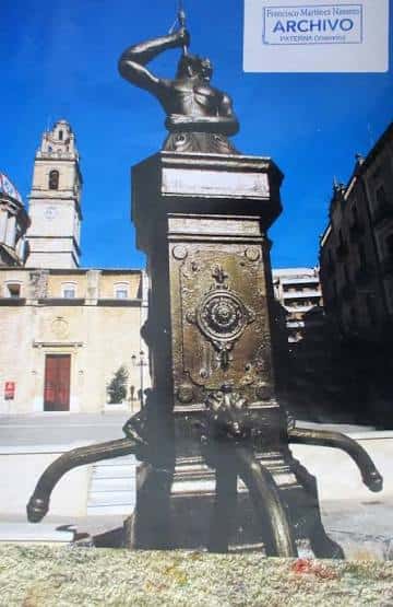 Fuente histórica en la Plaza del Pueblo con la iglesia al fondo