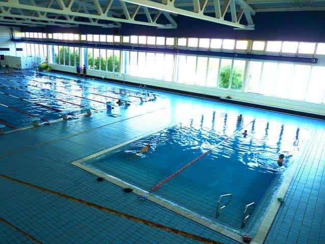 Vista general de la piscina climatizada con carriles de natación y personas nadando