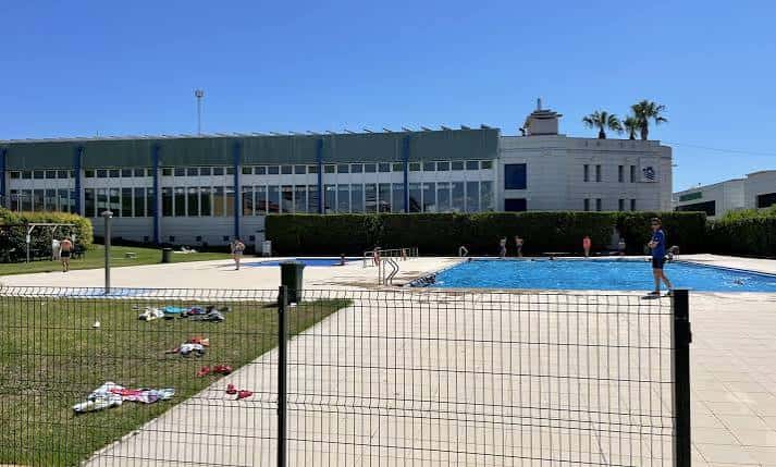 Vista exterior de la piscina municipal al aire libre con el edificio de fondo