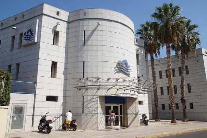 Fachada principal de la piscina municipal con palmeras y entrada