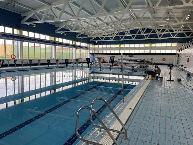 Interior de la piscina climatizada con estructura metálica y zona de descanso