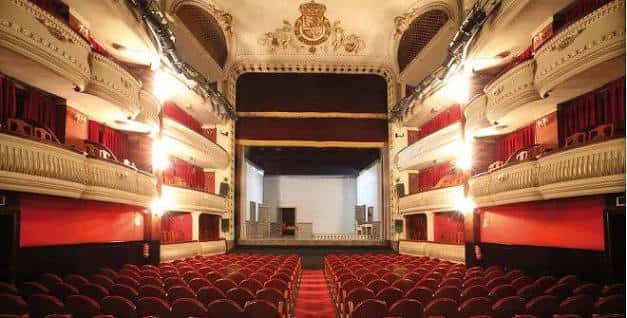 Interior del auditorio del Teatro Alcázar, con butacas rojas, palcos ornamentados y el escenario iluminado