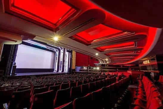 Vista panorámica del interior del teatro con iluminación roja y pantalla de cine