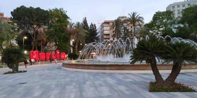 Vista panorámica de la Plaza Circular con fuente y letrero luminoso de Murcia al atardecer