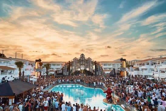Escenario principal frente a la piscina con multitud de asistentes al atardecer