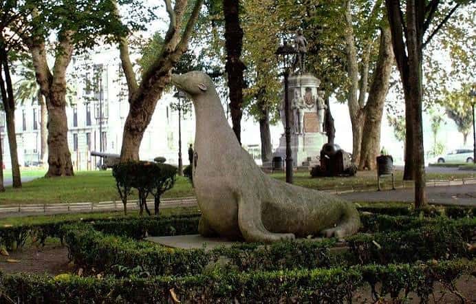Escultura de la foca en el Parque del Muelle, rodeada de setos y árboles