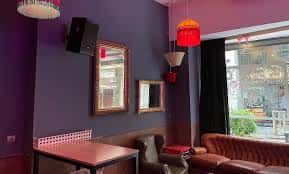 Interior del Söda Bar con paredes moradas, espejos y lámparas colgantes
