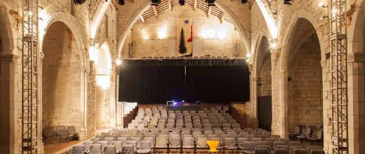 Interior del auditorio del Centre Cultural La Mercè con arcos de piedra y escenario preparado para evento
