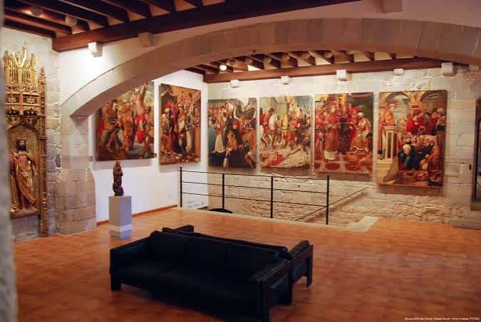 Sala de exposiciones con obras de arte religioso y arquitectura de madera y piedra