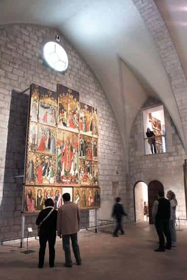 Visitantes observando un gran retablo en la sala principal del museo