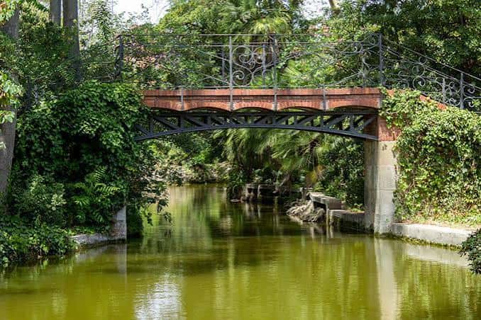Puente ornamental sobre el canal con reflejos en el agua y follaje verde