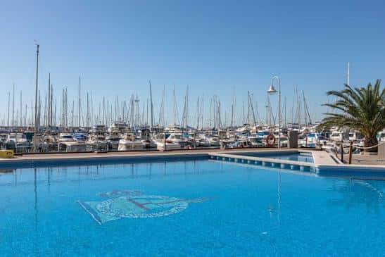 Piscina del club con el mar y veleros en el fondo