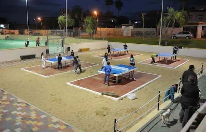 Zona de juegos de ping pong en el parque con personas disfrutando