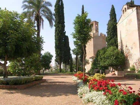 Paseo central de los jardines con palmeras, cipreses y macizos de flores