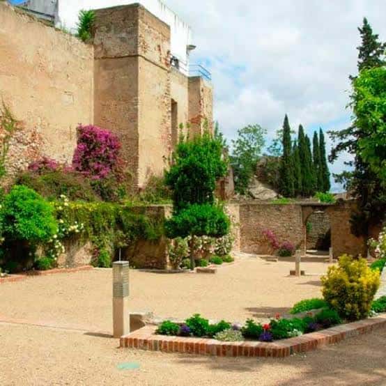 Plaza interior de los jardines con muros históricos y vegetación mediterránea
