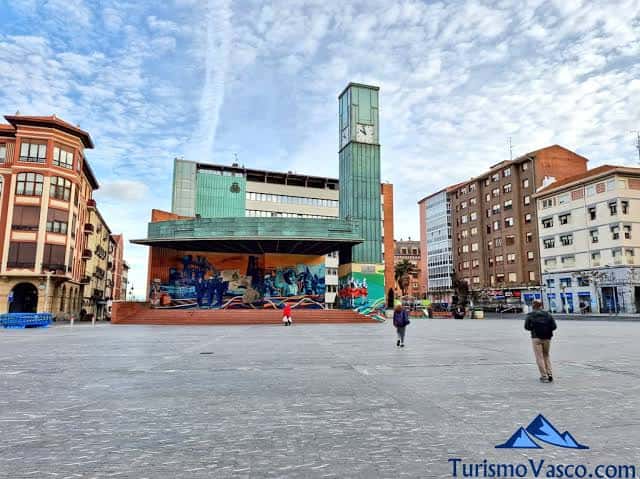 Plaza Herriko Plaza con el escenario y la torre del reloj bajo un cielo parcialmente nublado