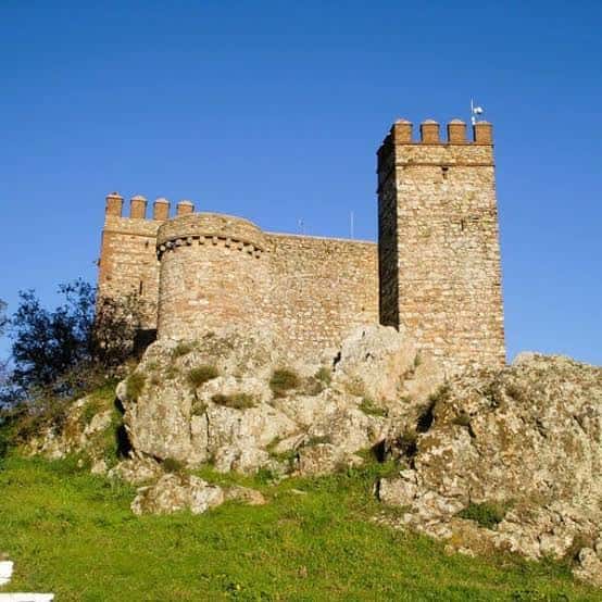 Fachada principal del castillo sobre el risco rocoso bajo un cielo azul despejado