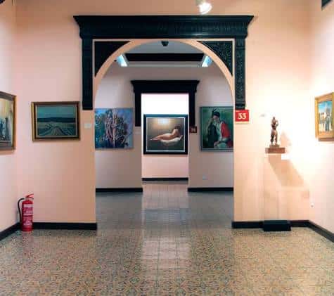 Pasillo interior con arco decorativo y obras de arte expuestas en paredes