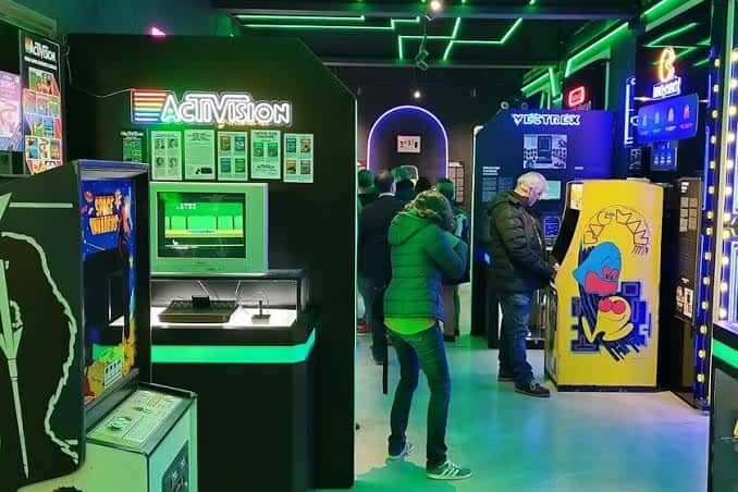 Zona de exhibición con consolas clásicas y visitantes interactuando