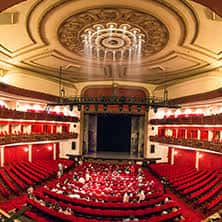 Interior del teatro con cúpula ornamentada y público en las butacas