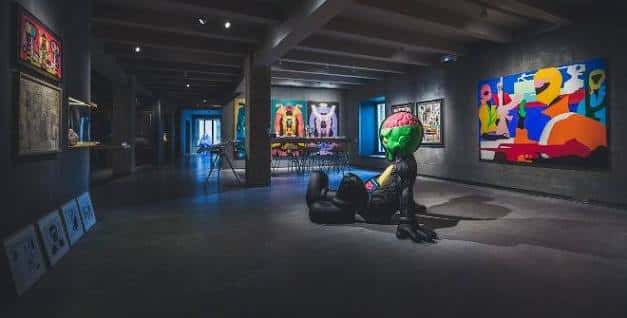 Sala de exposiciones con escultura de KAWS y obras de arte contemporáneo en las paredes