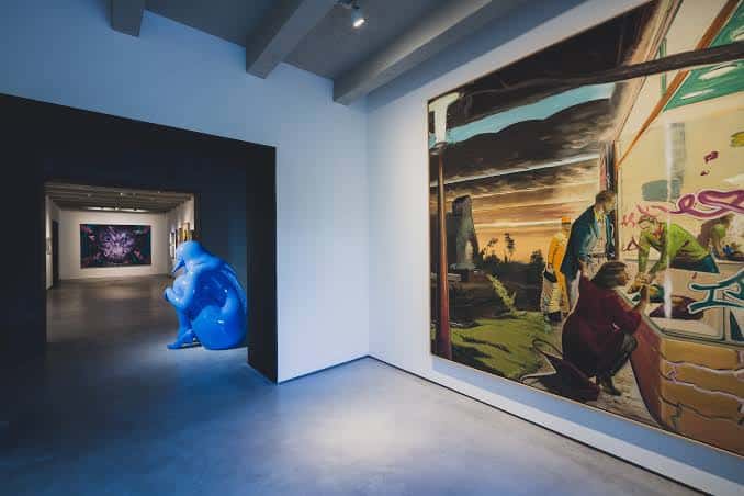 Galería con escultura azul y pintura mural de gran formato