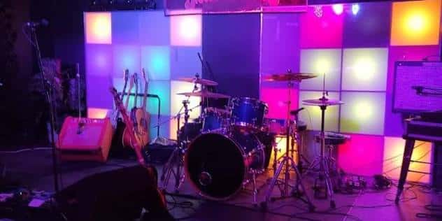 Detalle del escenario con batería y fondo de paneles luminosos