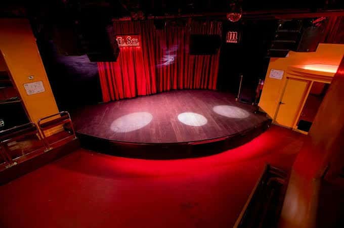 Plano cenital del escenario principal con iluminación de foco y cortinas rojas de fondo