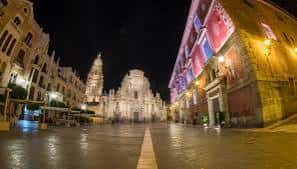 Plaza del Cardenal Belluga iluminada por la noche con fachadas decoradas y ambiente festivo