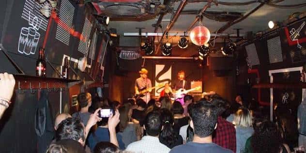 Concierto en vivo en el interior de Sala Juglar con banda en el escenario y público