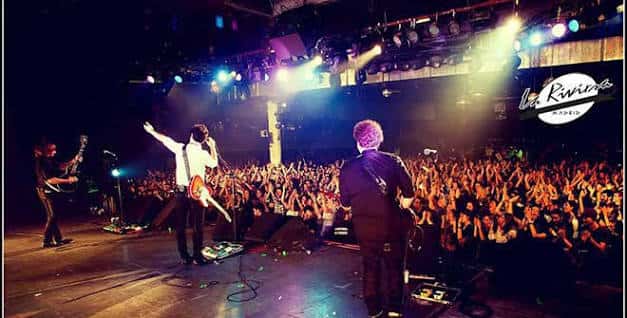 Concierto en vivo con banda en el escenario y multitud de espectadores