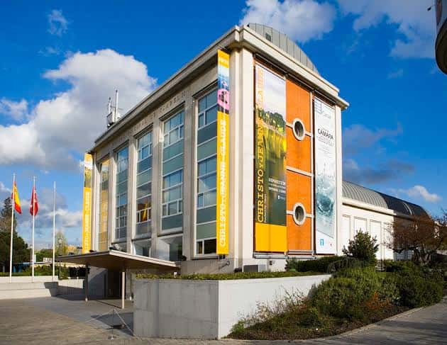 Exterior de la Fundación Canal con carteles de exposiciones y banderas españolas en el patio