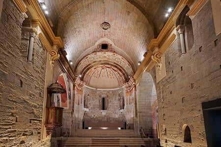 Interior de la iglesia con bóvedas de piedra y detalles arquitectónicos medievales