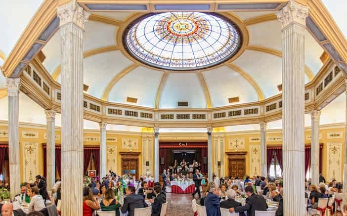 Gran salón circular con cúpula de vidrio y columnas durante un evento social