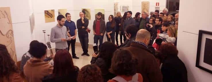 Evento cultural en interior con público y obras expuestas