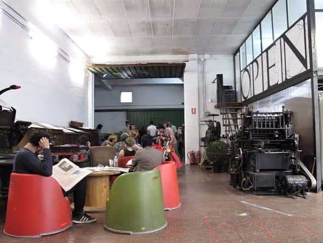 Interior del espacio Open con mobiliario industrial y visitantes