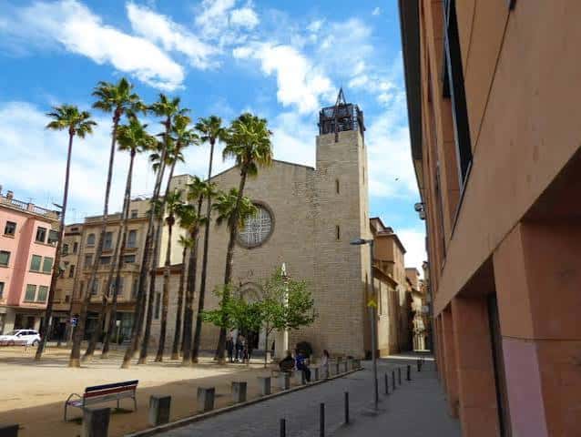 Fachada exterior de la Iglesia de Santa Susanna con palmeras y cielo azul