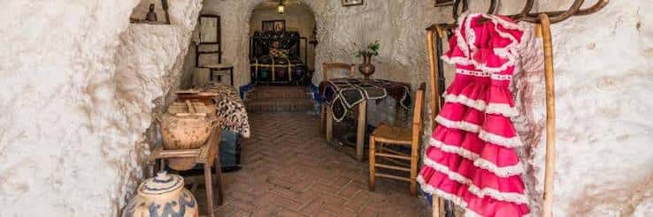 Interior de cueva decorada con vestimenta flamenca y mobiliario tradicional