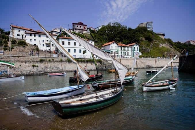 Barcos tradicionales de vela latina amarrados en el puerto con el casco histórico al fondo