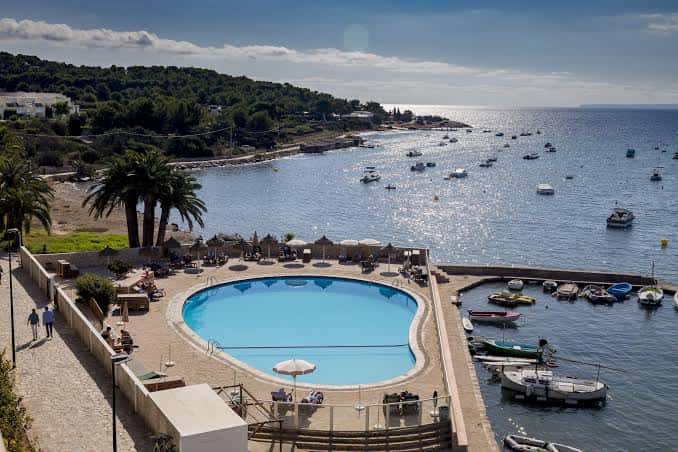 Piscina del hotel frente al puerto con barcos y mar abierto