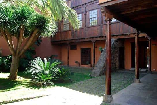 Patio interior del museo con galería de madera, columnas y vegetación tropical