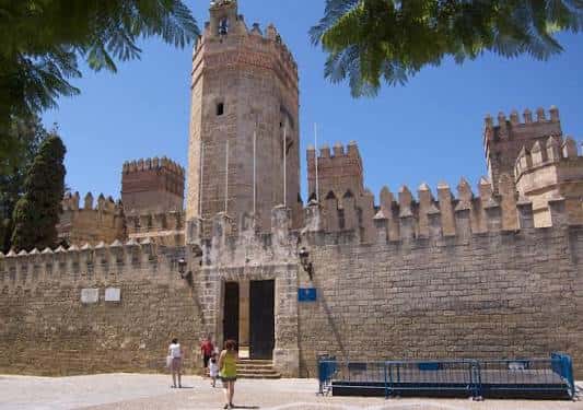 Vista frontal de la Torre del Homenaje y murallas de la Plaza Alfonso X El Sabio con visitantes
