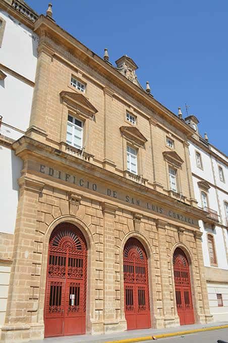 Fachada principal del Edificio San Luis Gonzaga con puertas rojas y detalles arquitectónicos en piedra