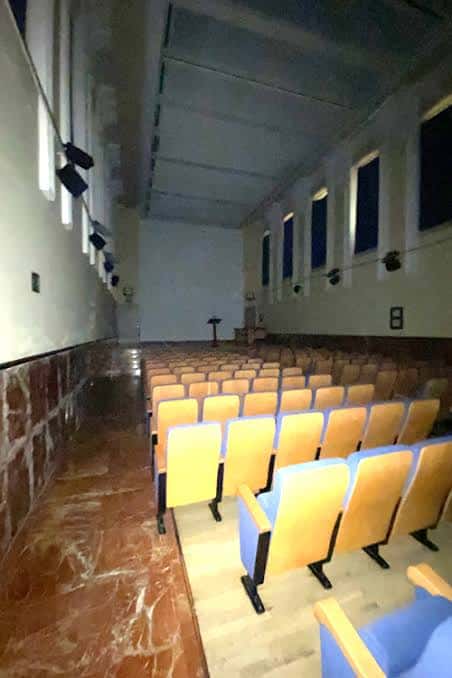 Interior del auditorio del Edificio San Luis Gonzaga con butacas amarillas y azules dispuestas para eventos
