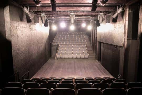 Interior del teatro con iluminación de escenario y butacas vacías