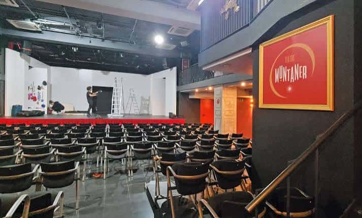 Interior del teatro con cartel de Teatre Muntaner y personal en el escenario