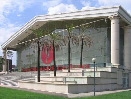 Fachada frontal del teatro con palmeras y logotipo rojo visible