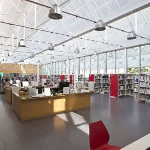Interior luminoso de la biblioteca con estanterías, zona de lectura y mobiliario moderno