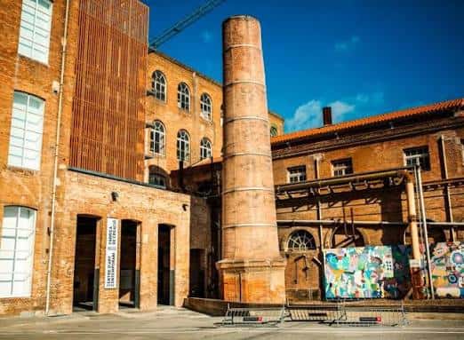 Vista exterior del patio de la fábrica con grafitis y chimenea