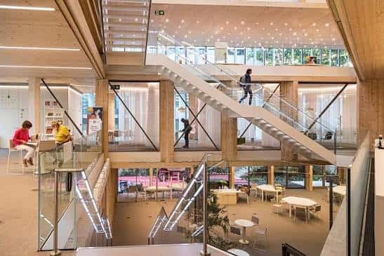 Interior de la biblioteca con escaleras y áreas de lectura